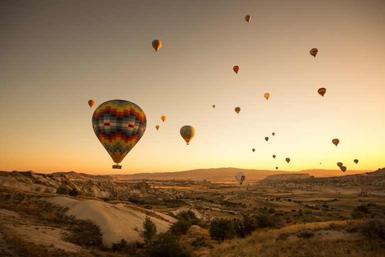 A set of colored balloons flying above the ground in Cappadocia, Türkiye
